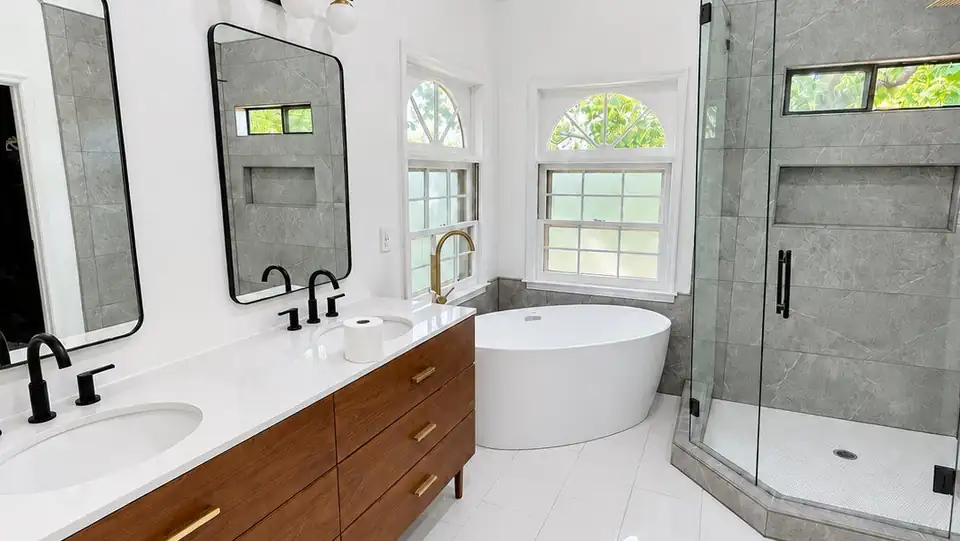 Bathroom remodeling in Dawsonville, GA by Trophy Tile: white freestanding tub, walnut double vanity, black framed mirror and a glass-enclosed tile shower
