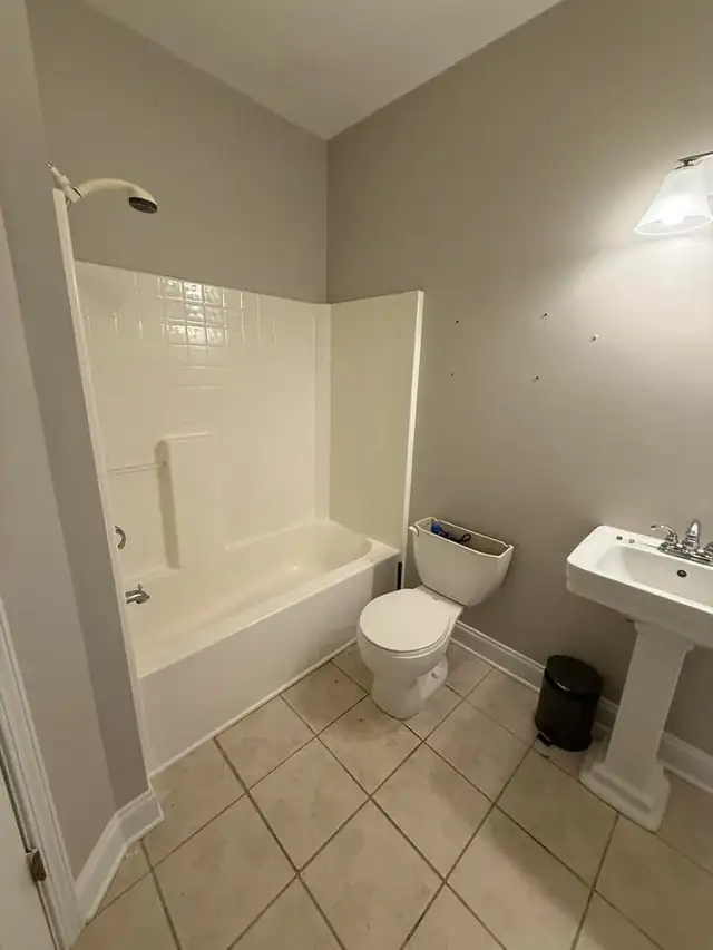 Bathroom before remodel with a fiberglass tub and shower unit and pedestal sink